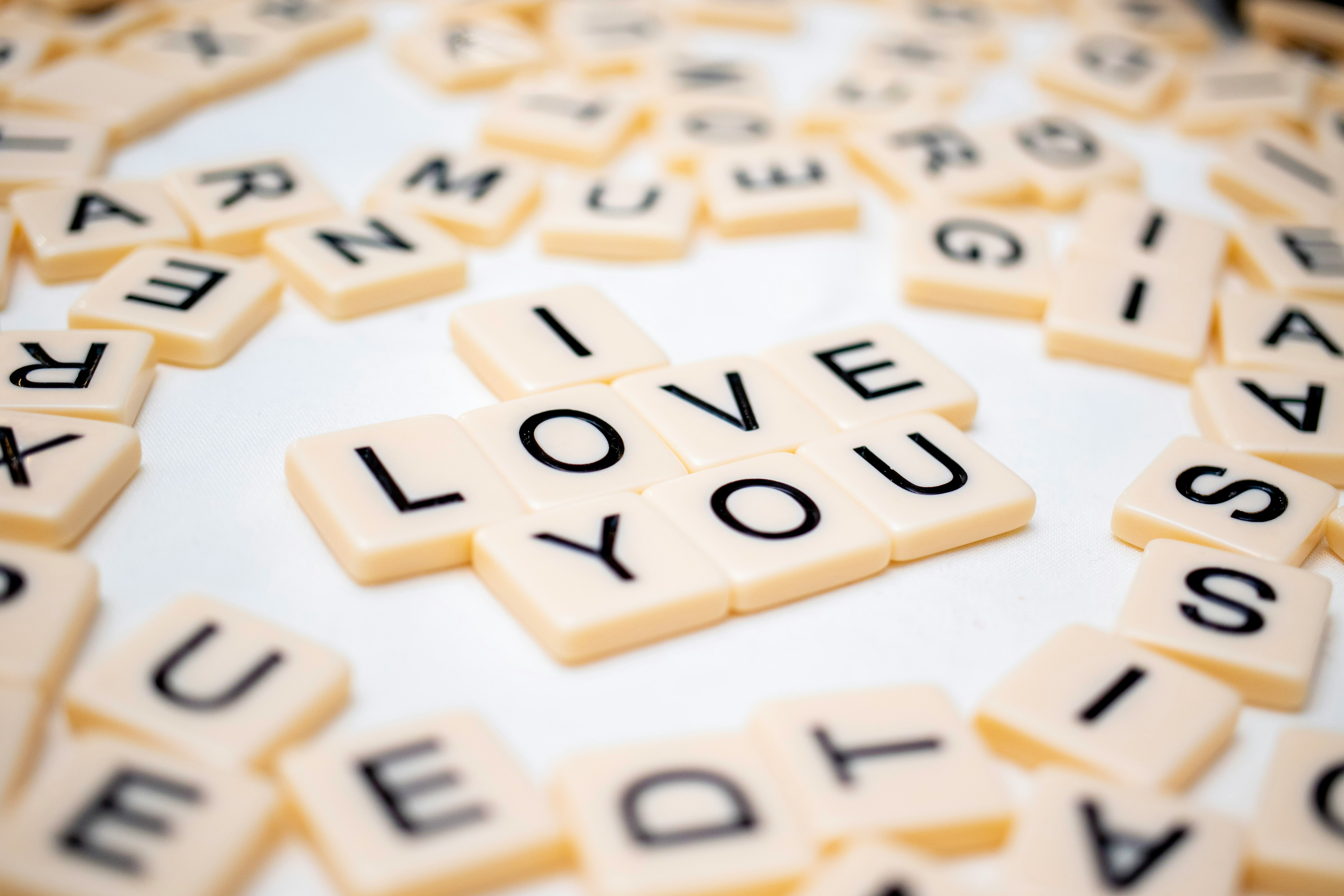 Macro photo of "I love you" spelt in letter tiles on a white background, surrounded by scattered files. 