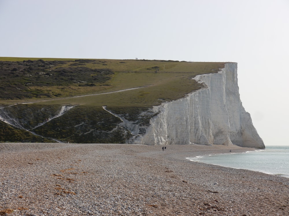 brown and green mountain beside body of water during daytime