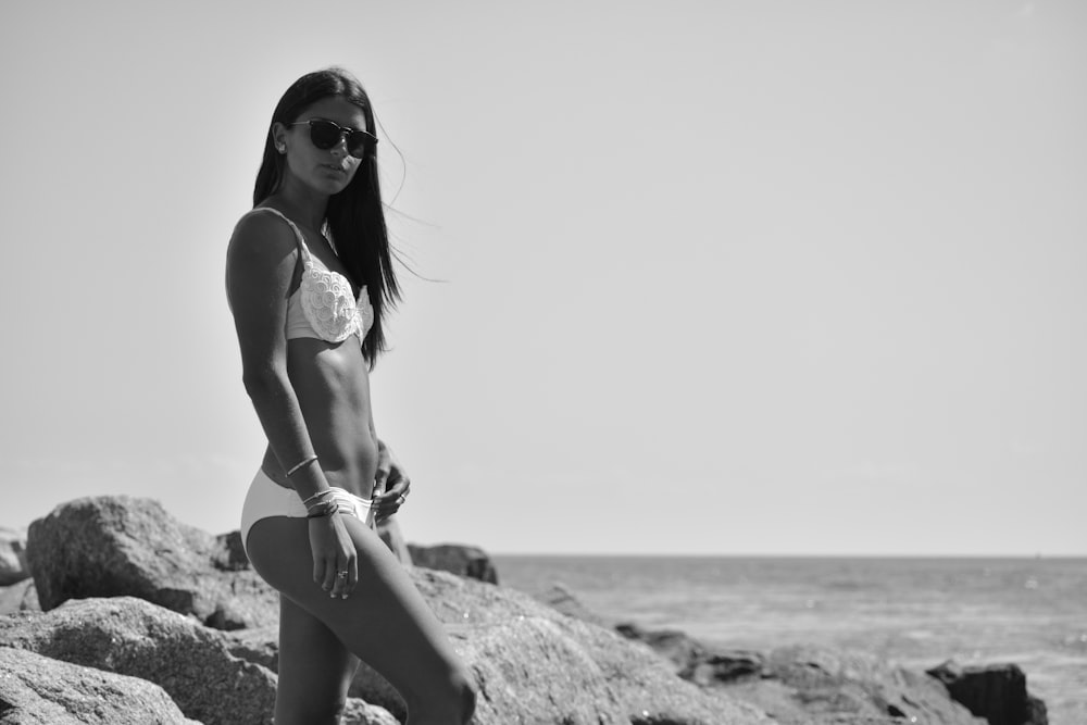 woman in bikini sitting on rock