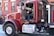 Close-up of a truck driver checking paperwork beside a parked tractor-trailer.