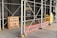 Outdoor scaffolding with metal poles surrounds a building under renovation. A wooden board displays the message 'It takes a child to raze a village. Paul Richard'. Nearby, a yellow construction dumpster is placed, along with an orange ladder leaning against the scaffold. A person wearing a hard hat and mask stands nearby, possibly a construction worker.