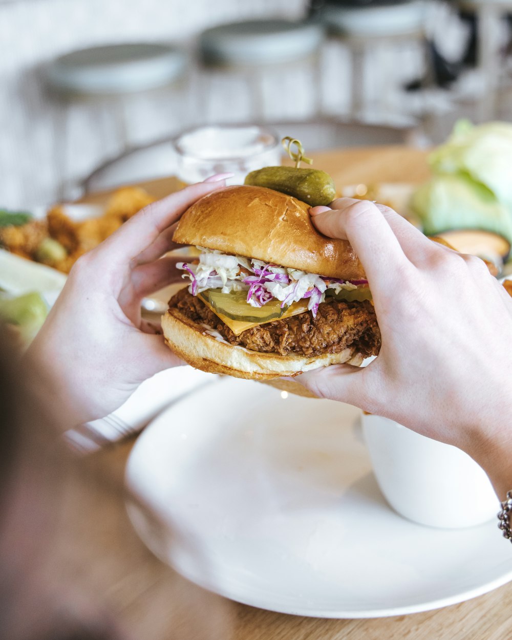 person holding burger with lettuce and tomato