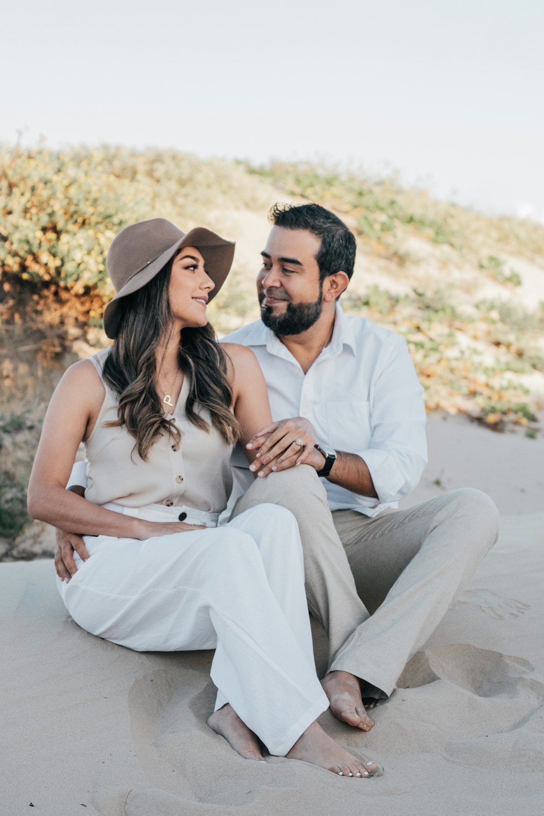 man in white button up shirt sitting beside woman in white sleeveless dress