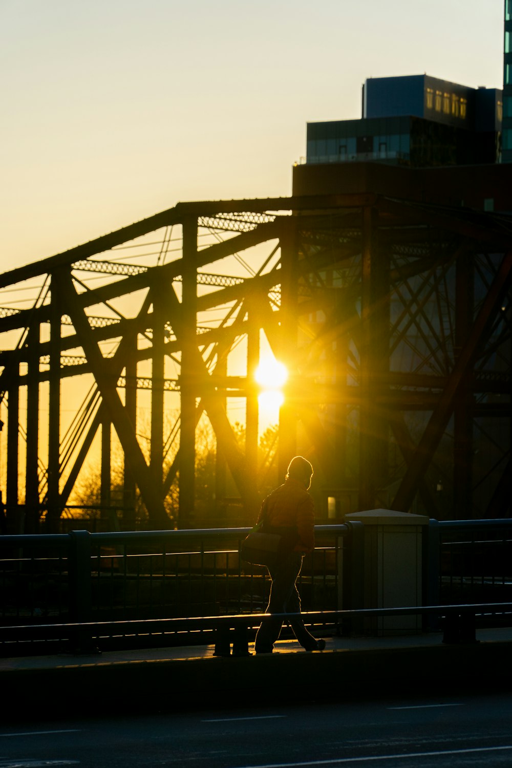 man and woman sitting on bench near bridge during sunset