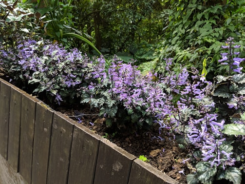 A sturdy wooden planter box filled with vibrant flowers sitting on a porch.