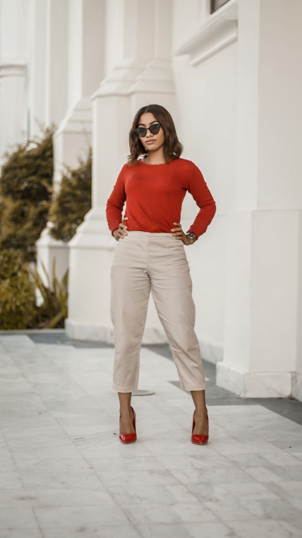 Foto Mujer con camisa roja de manga larga y pantalones marrones junto a pared blanca durante el día – Imagen República dominicana gratis en Unsplash