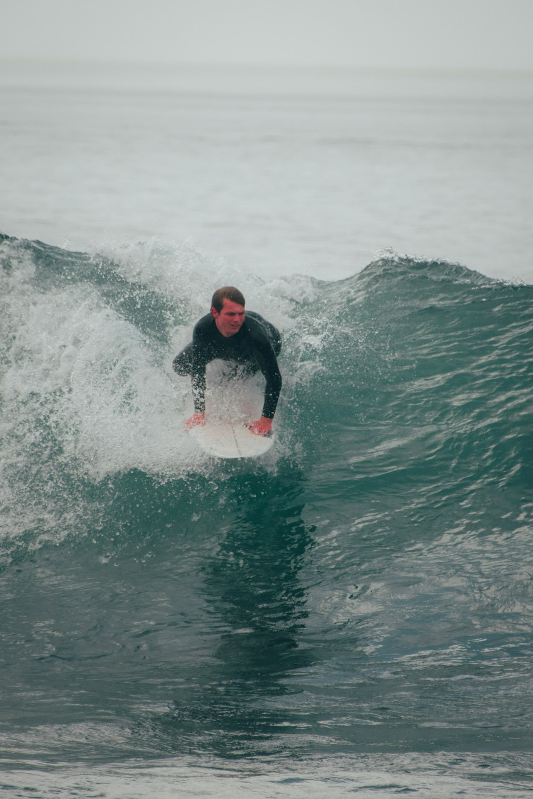 man in black and red hoodie surfing on water during daytime
