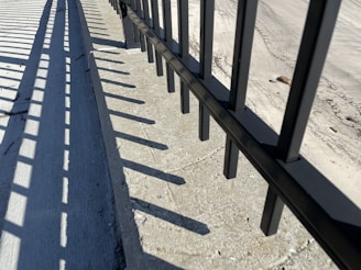 Close-up of a sleek black aluminum picket fence with a weather-proof powder-coated finish glistening under sunlight.