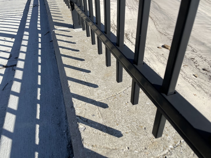 Close-up of a sleek black aluminum picket fence with a weather-proof powder-coated finish glistening under sunlight.