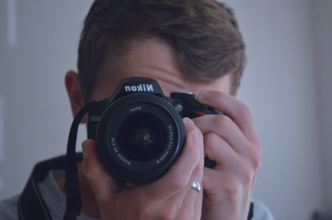 man holding black nikon dslr camera,
