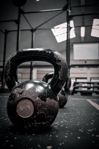 Close-up of sturdy kettlebells stacked on a gym floor with natural light highlighting their texture