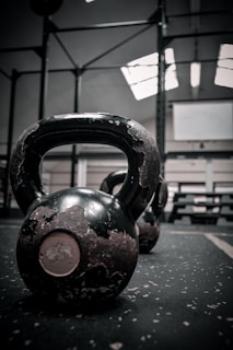 Close-up of a heavy-duty iron kettlebell resting on a textured gym floor, highlighting its rugged design.