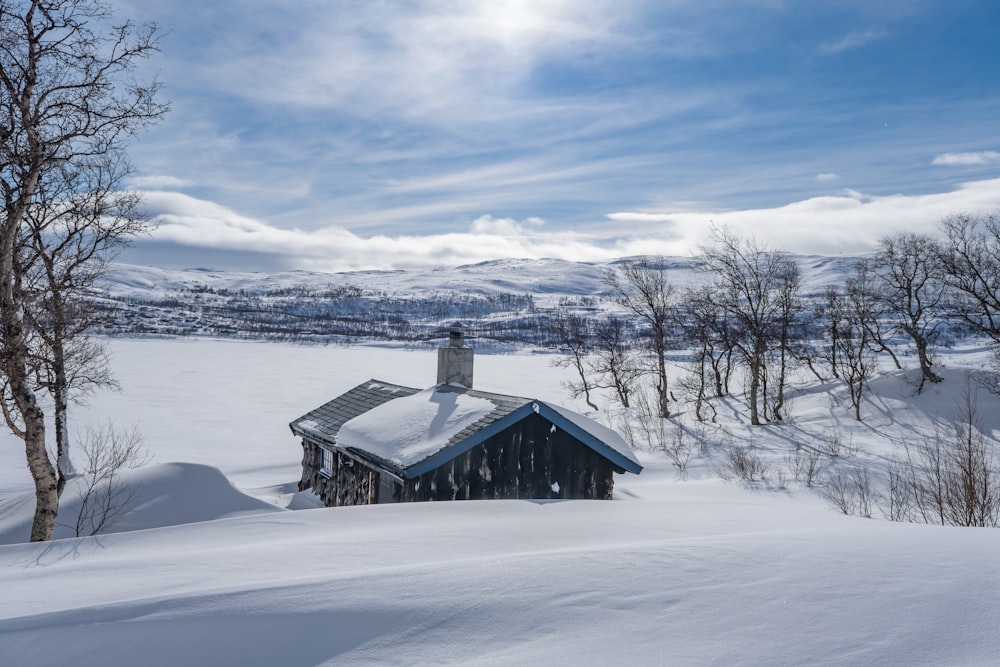 brown wooden house on snow covered ground under white clouds and blue sky during daytime