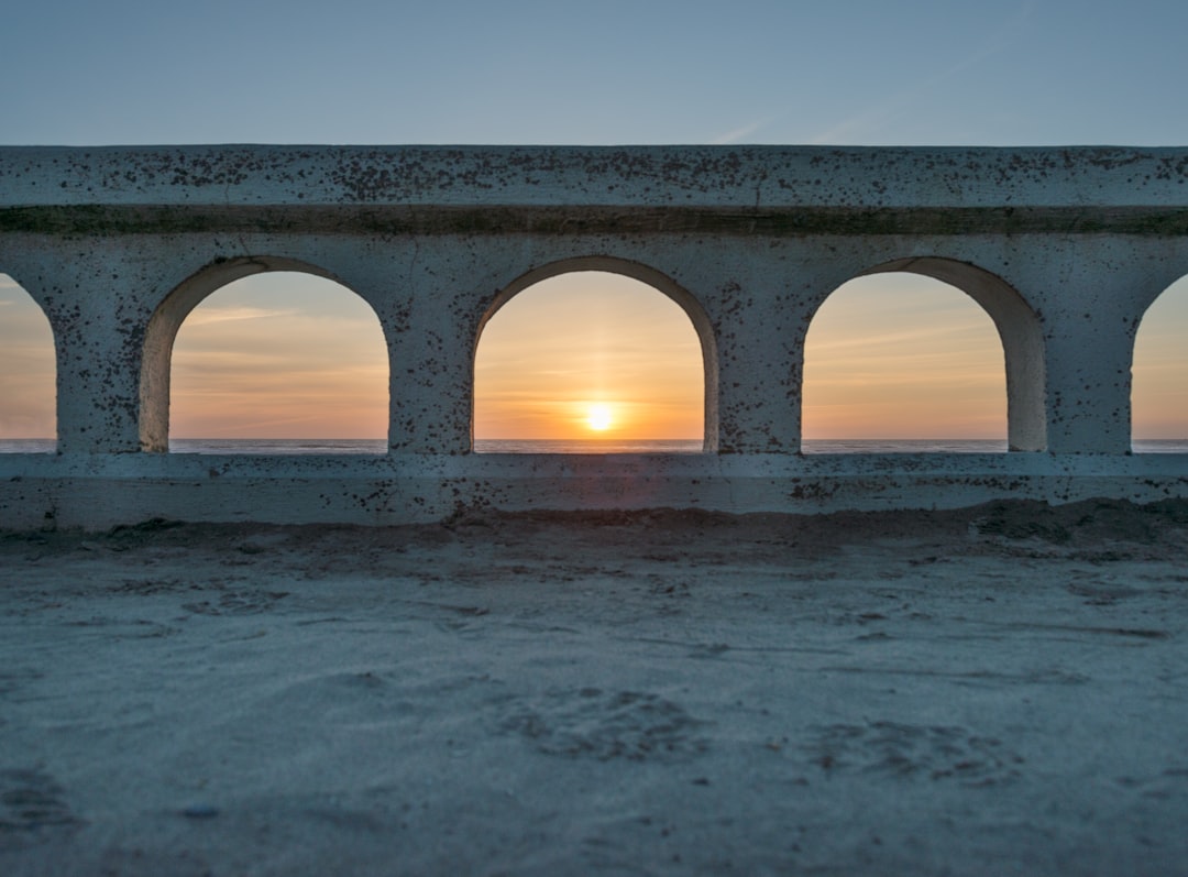 white concrete bridge over the sea during sunset