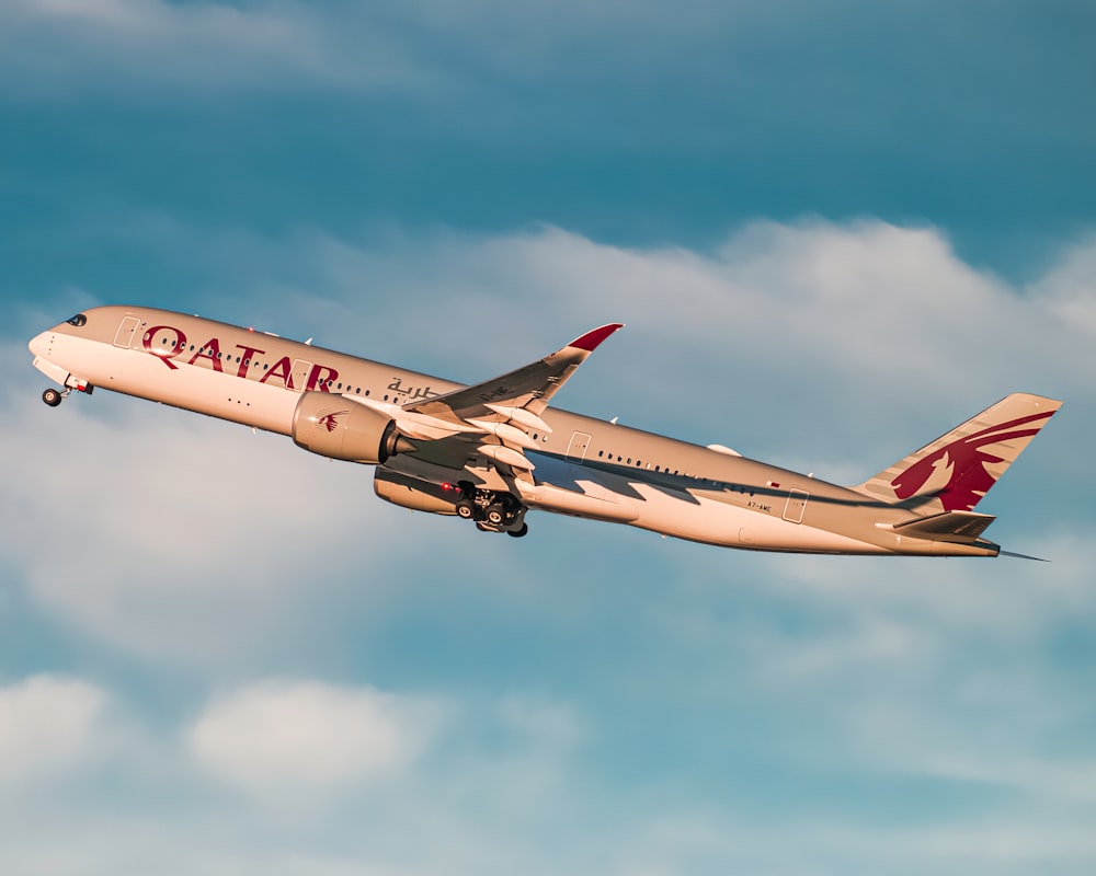 weißes und rotes Flugzeug, das tagsüber am Himmel fliegt