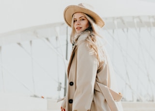 woman in brown coat wearing brown hat standing on snow covered ground during daytime