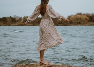 woman in white dress standing on sea shore during daytime