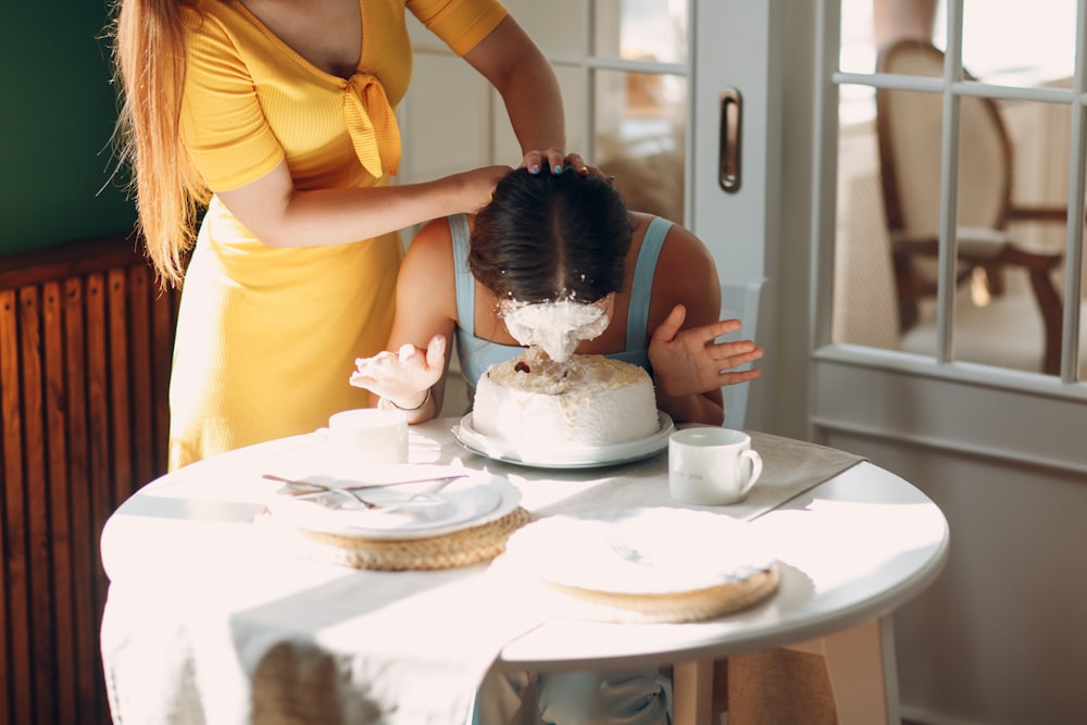 Femme en chemise jaune tenant une fille en robe blanche