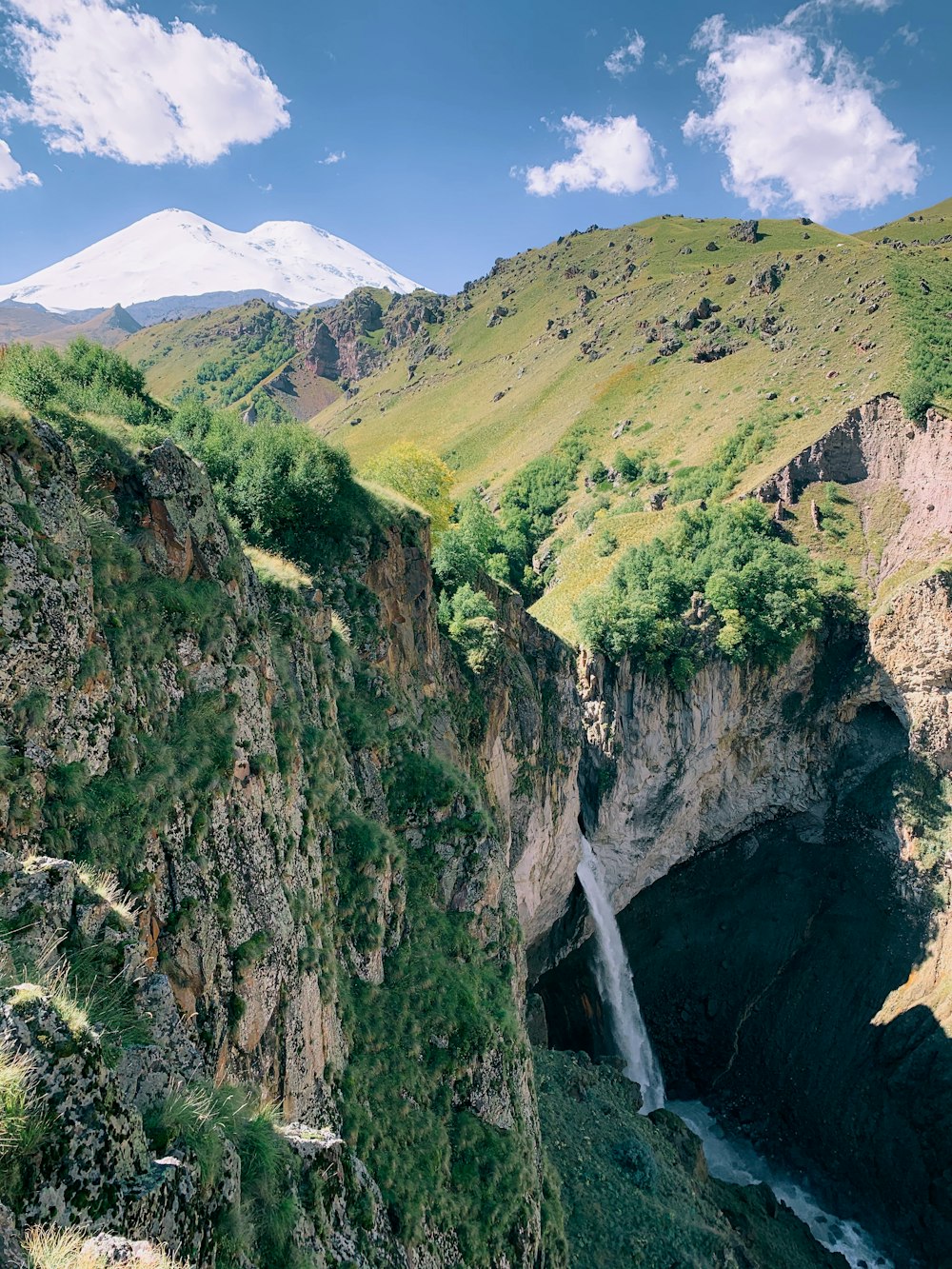 green and brown mountain with waterfalls during daytime