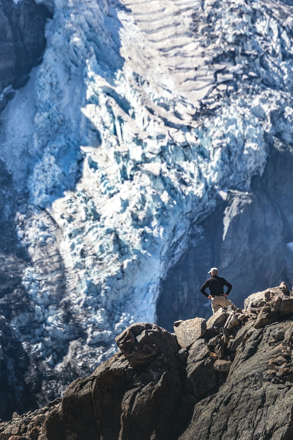 man in black jacket and black pants sitting on rock formation during daytime