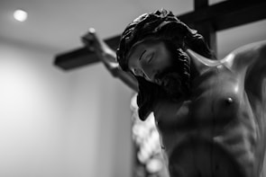 A close-up photograph of a wooden carving of Jesus with gentle expressions.