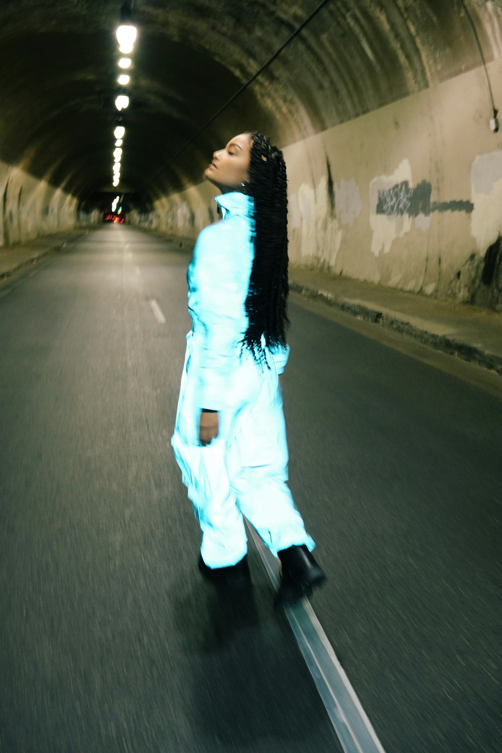 woman in white long sleeve shirt and white pants walking on road during daytime