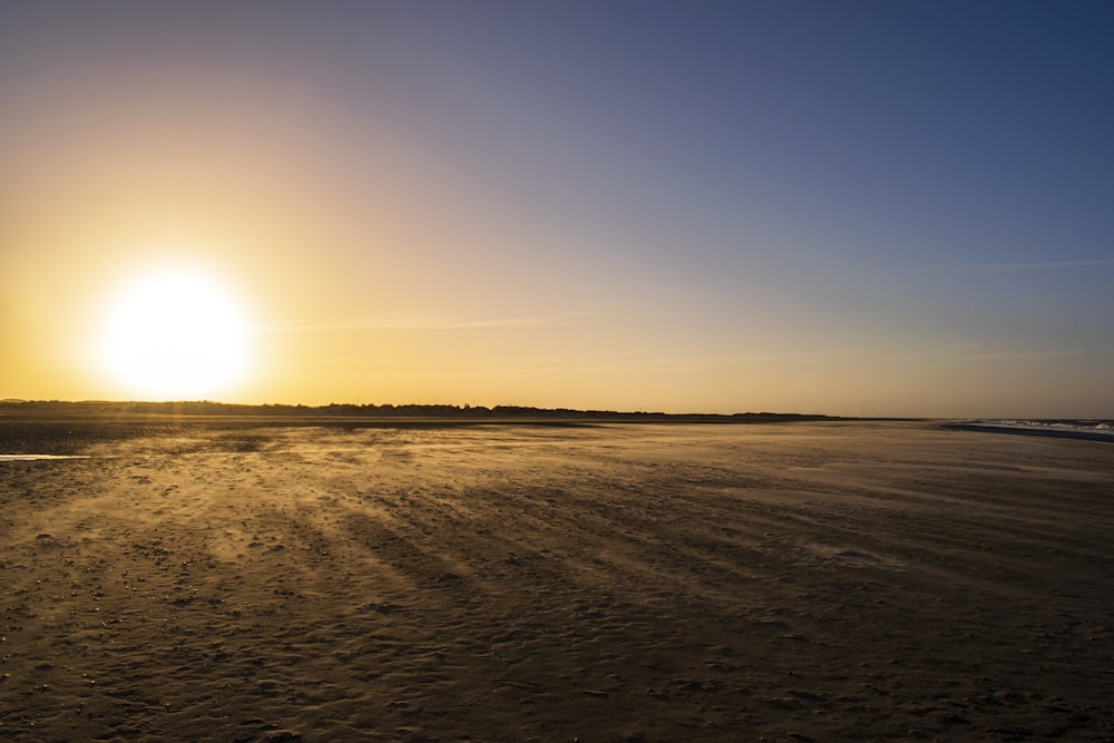 sable brun sous le ciel bleu au coucher du soleil