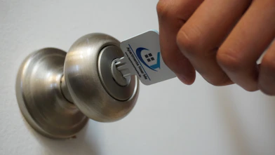 A friendly hotel receptionist handing a key card to a smiling guest at the front desk.