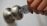 A hand is seen holding a key card, inserting it into a modern doorknob with a built-in lock. The key card has a logo and some text printed on it.