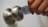 A hand is seen holding a key card, inserting it into a modern doorknob with a built-in lock. The key card has a logo and some text printed on it.