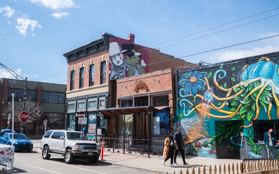 A lively scene of travelers chatting with a local artist beside colorful Berlin street art murals.