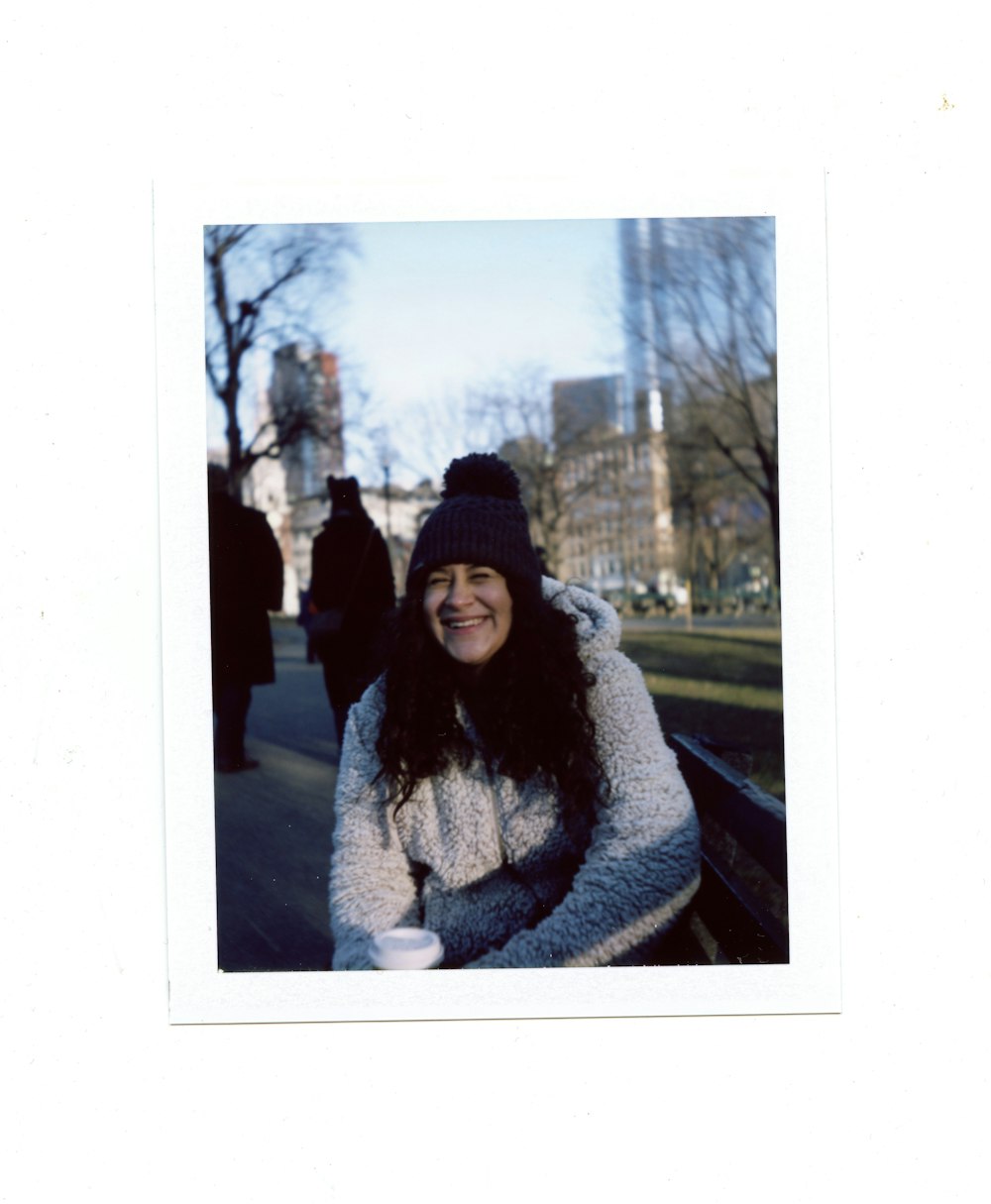 woman in gray coat standing near bare trees during daytime