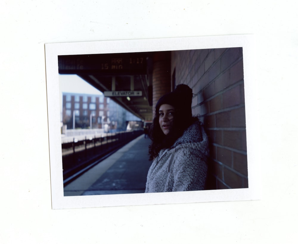 woman in white fur coat standing on sidewalk during night time