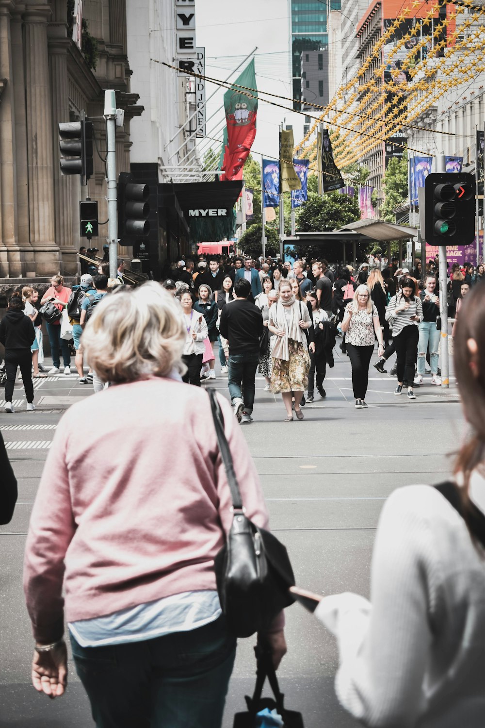 woman in pink jacket walking on pedestrian lane during daytime