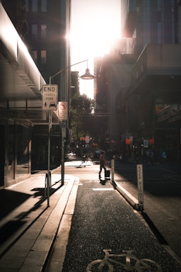 A traveler pulling a durable, expandable suitcase down a bustling city street under bright sunlight.