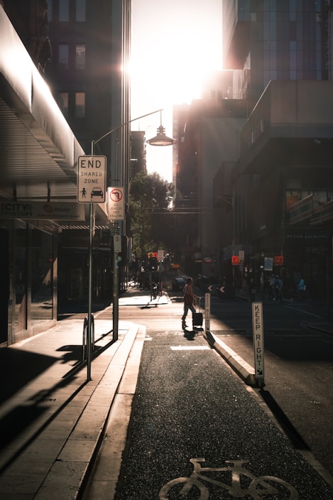 A traveler pulling a durable, expandable suitcase down a bustling city street under bright sunlight.