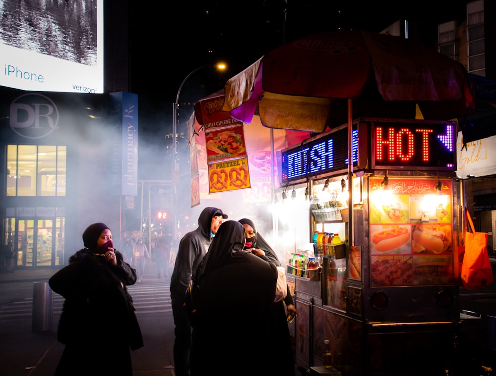 man in black jacket standing near store during night time