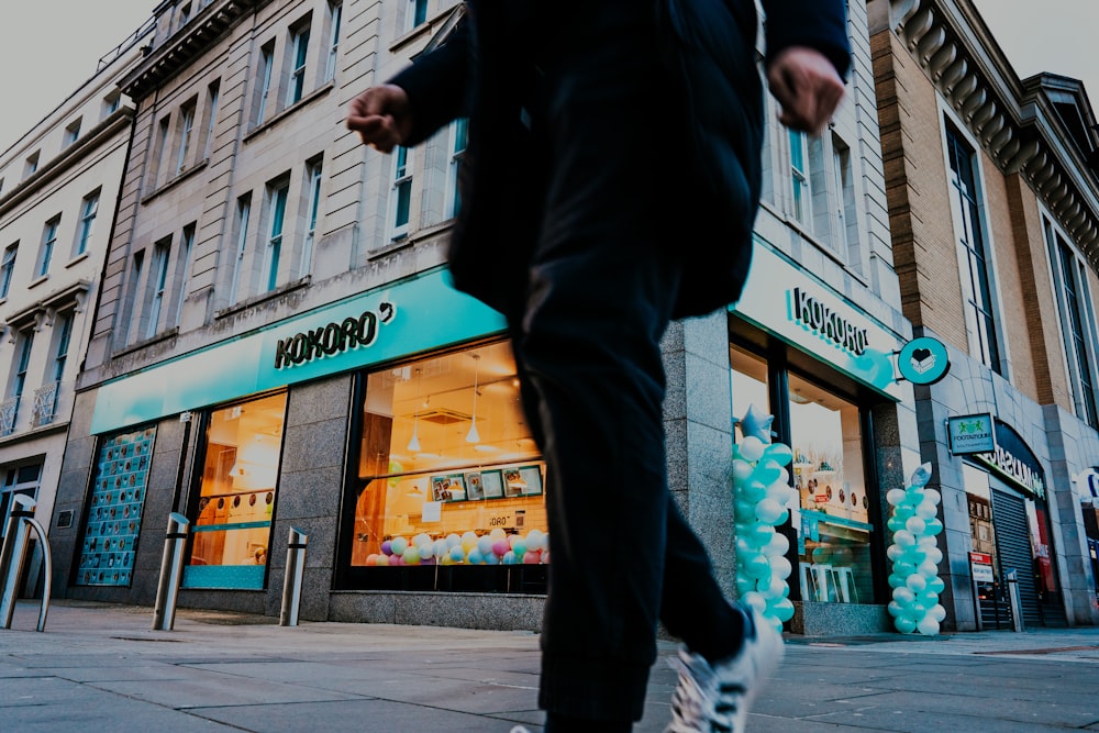man in black jacket and black pants walking on sidewalk during daytime