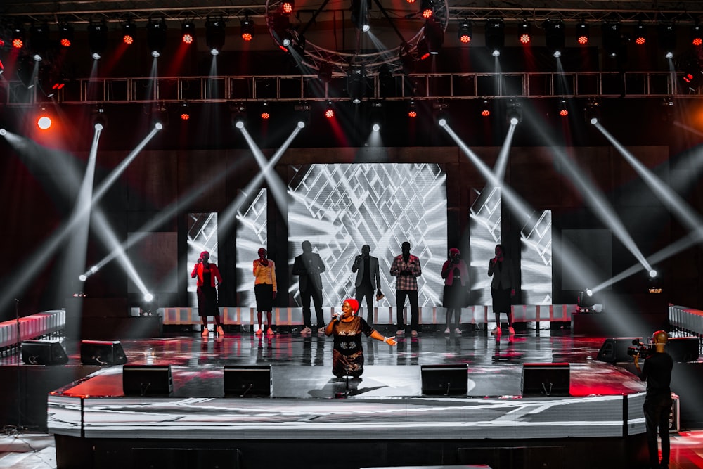 Personas de pie en el escenario con las luces encendidas durante la noche