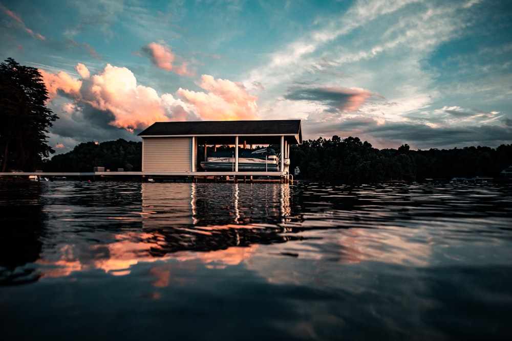 Weißes Holzhaus auf dem Wasser unter blauem Himmel und weißen Wolken tagsüber