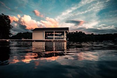 white wooden house on water under blue sky and white clouds during daytime