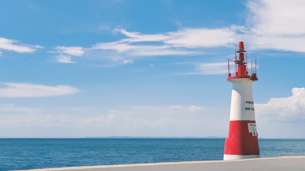 red and white lighthouse on beach during daytime