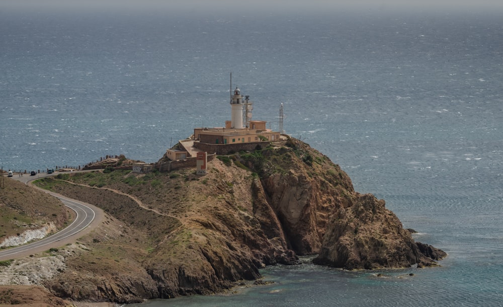 white lighthouse on brown rock formation near body of water during daytime