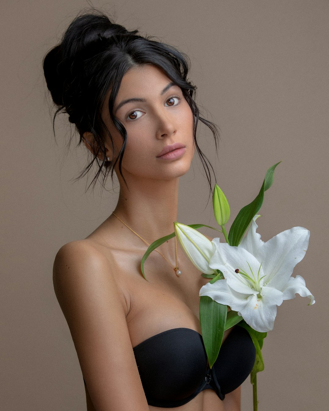 woman in black brassiere holding white flower