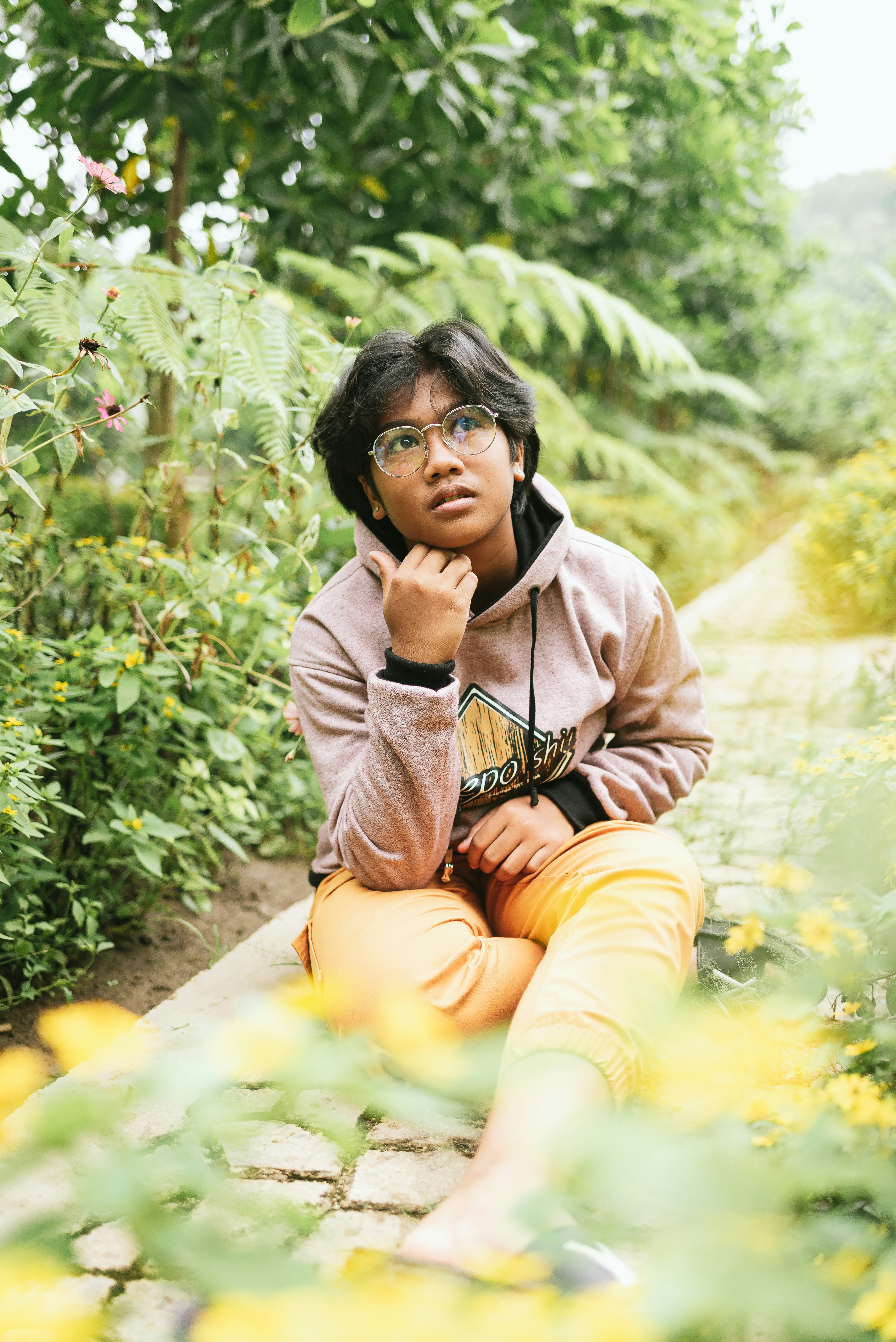 woman in brown hoodie sitting on green grass during daytime