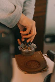 A sleek espresso machine with a barista’s hand gently tamping the coffee grounds.