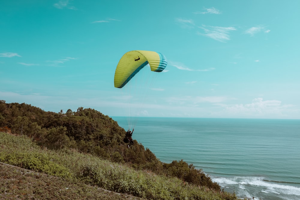 parachute jaune et vert au-dessus de la mer pendant la journée