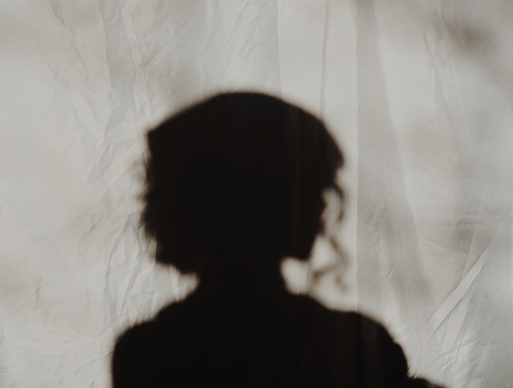 silhouette d’une personne debout près d’un textile blanc