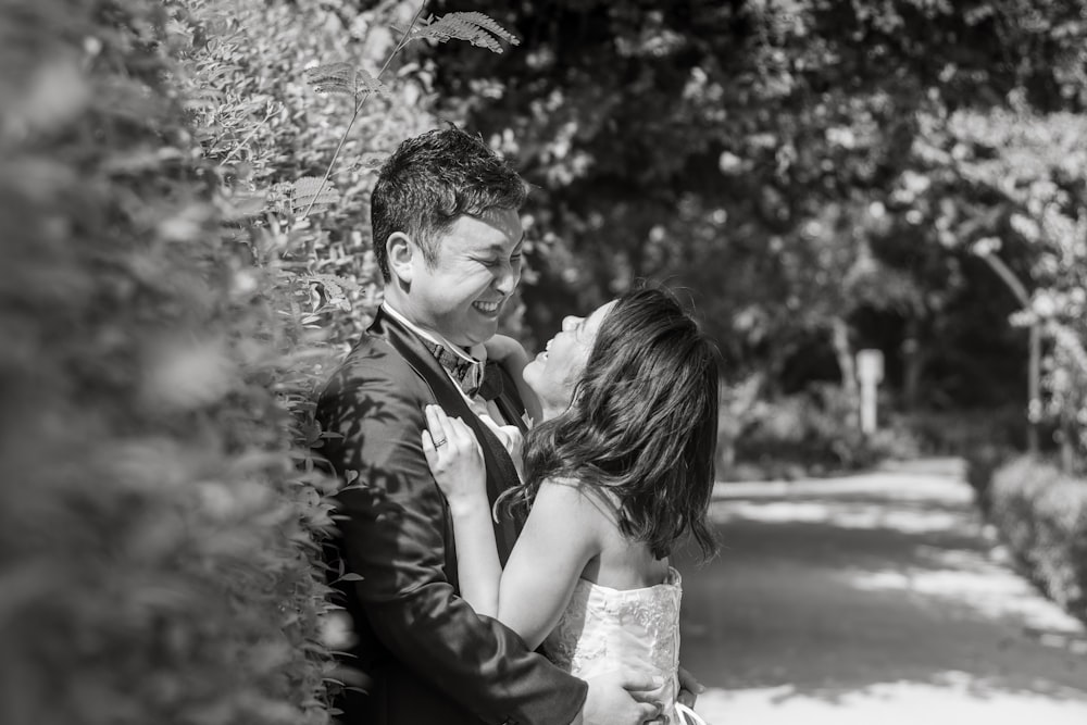 man and woman kissing on the road in grayscale photography