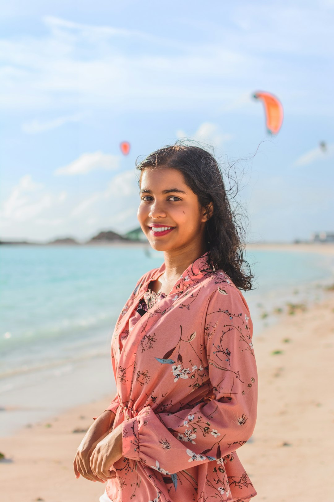 woman in pink and white floral robe standing on beach during daytime